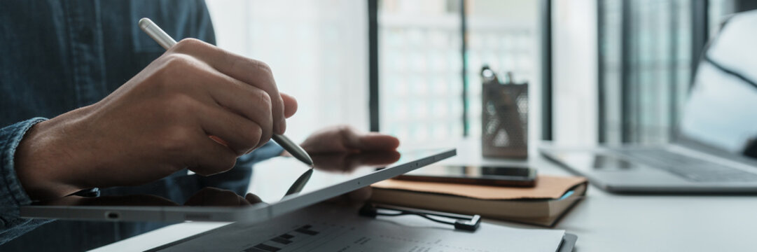 Focused businessman checking reports and verifying office documents with calculator and paper files on table
