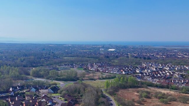 Irvine, North Ayrshire, Scotland, showing residential housing, green spaces, urban expansion and coastal landscape under cool blue atmospheric light, aerial view