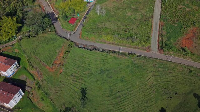 Aerial view rising over green fields to reveal colorful colonial town buildings in Jerico