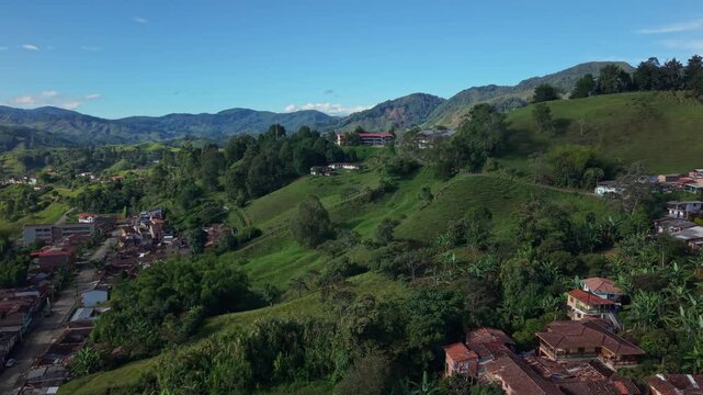 Aerial view approaching colorful church and hillside town in lush Jerico, Colombia
