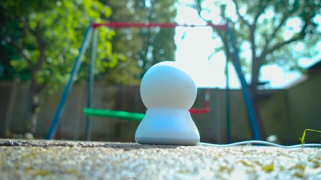 Outdoor child safety camera monitoring backyard playground and swing area. Smart AI surveillance device supporting remote family supervision and connected home security in garden setting. Playground