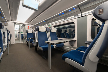 Obraz premium Empty interior of modern high speed train passenger carriage with blue seats and foldable tables. Clean cabin of intercity express for travel commute transportation tourism business trip.