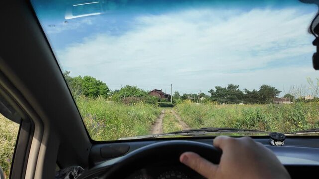 POV of driving a car on a dirt road through green summer fields. Cinematic 4K 24fps footage with realistic motion blur, capturing an adventurous countryside road trip under a blue cloudy sky.