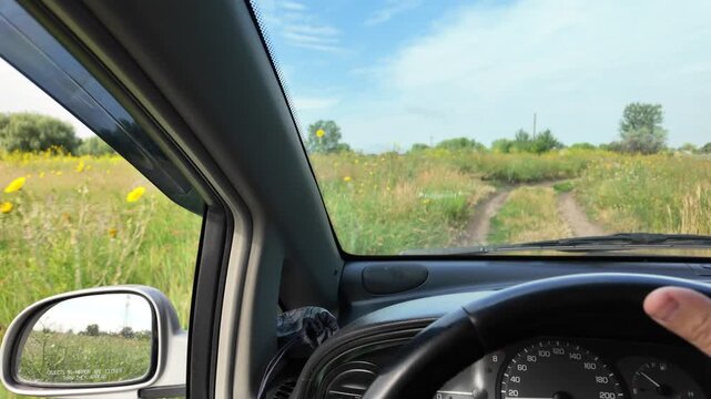 POV of driving a car on a dirt road through green summer fields. Cinematic 4K 24fps footage with realistic motion blur, capturing an adventurous countryside road trip under a blue cloudy sky.
