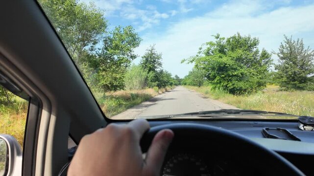 POV of driving a car on a dirt road through green summer fields. Cinematic 4K 24fps footage with realistic motion blur, capturing an adventurous countryside road trip under a blue cloudy sky.