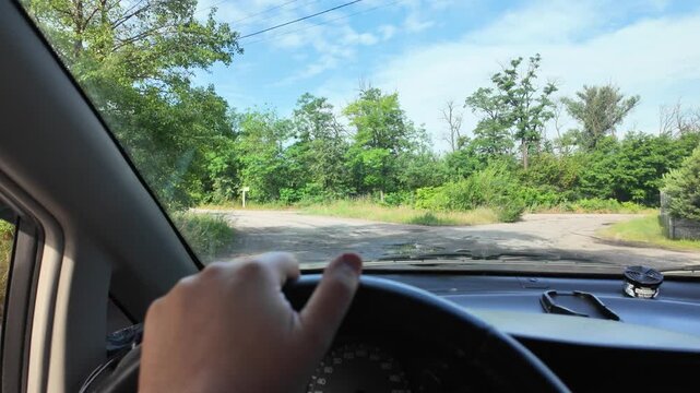 POV of driving a car on a dirt road through green summer fields. Cinematic 4K 24fps footage with realistic motion blur, capturing an adventurous countryside road trip under a blue cloudy sky.