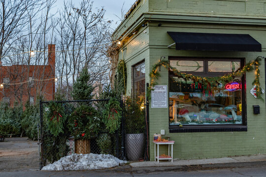 Festive corner store adorned with holiday garlands and a bright neon open sign at dusk.