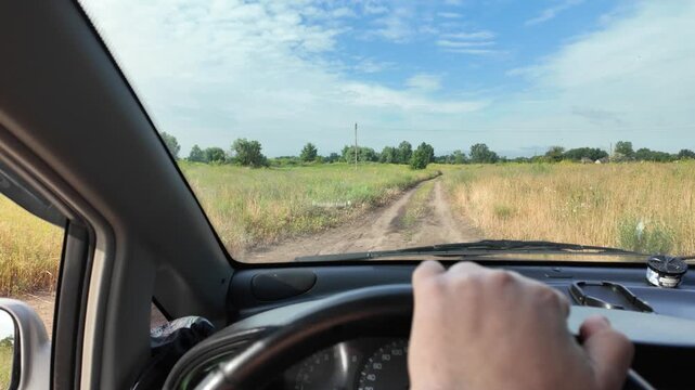 POV of driving a car on a dirt road through green summer fields. Cinematic 4K 24fps footage with realistic motion blur, capturing an adventurous countryside road trip under a blue cloudy sky.