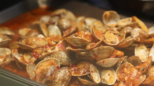 Steamed clams in marinara sauce served in warm restaurant evening light
