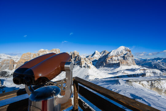 Scenic view of snowy mountains and a coin-operated binocular telescope on a sunny day.