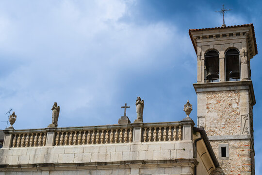 Historic stone church tower with statues under a vibrant blue sky.