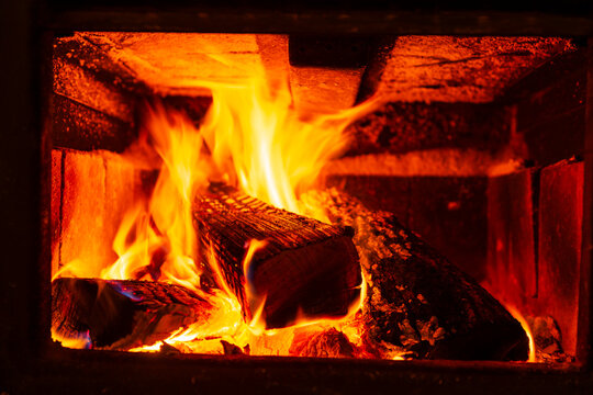 Bright flames dance around logs inside a cozy, rustic fireplace.