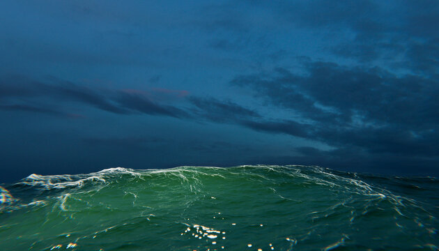 Ocean waves under a dramatic evening sky with dark clouds and hints of deep blue and green. Illustration, rendering