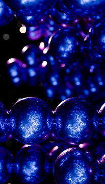 Close-up of shiny blue metallic spheres interconnected against a dark background. Illustration, rendering