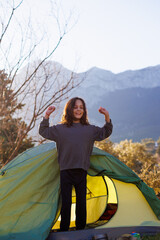 Obraz premium happy child comes out of the tent and looks at the mountains. child in a tent. outdoor recreation.