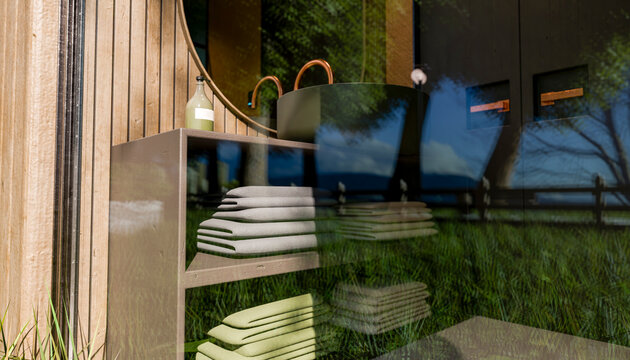 Elegant modern bathroom with stacked towels, round mirror, and view of lush greenery outside.
