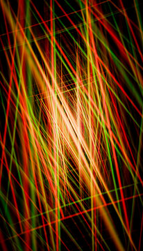 Abstract red, green, and yellow light streaks crossing on a black background.