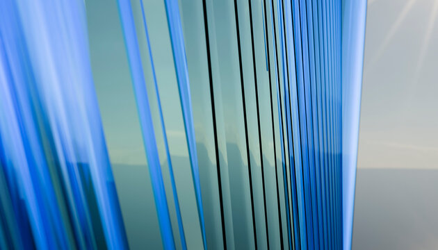 Blue-toned glass windows reflect sunlight, creating sleek modern lines against the sky.