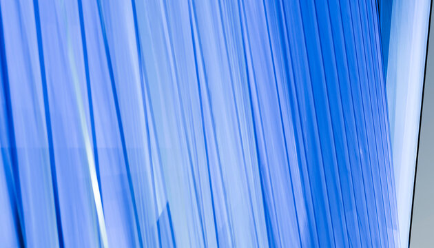 Abstract view of modern glass building with blue vertical lines and reflections.