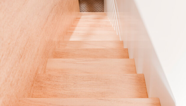 A wooden staircase leading down to a herringbone-patterned wooden floor in soft lighting.
