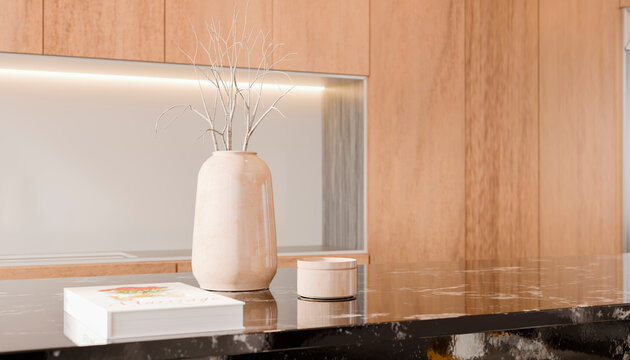 Modern kitchen countertop with vase, book, and wooden cabinets in warm tones.