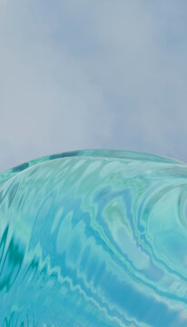 Clear blue wave against a soft sky on a sunny day.