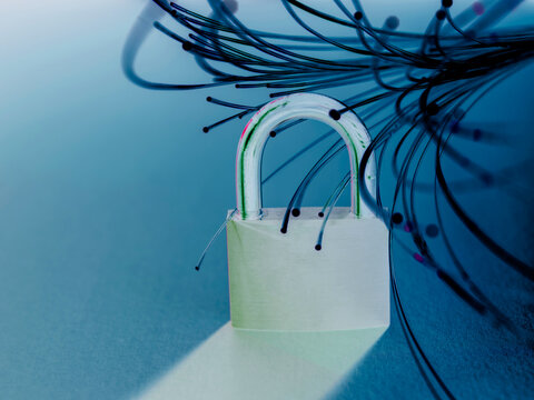 A padlock entangled with fiber optic cables on a reflective blue surface.