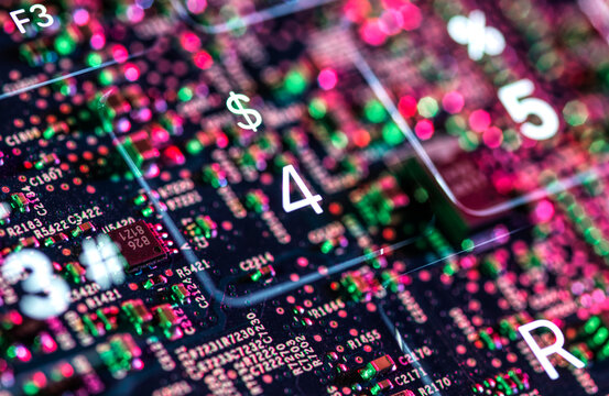 Close-up of colorful illuminated circuit board with numbers and symbols seen through glass. 