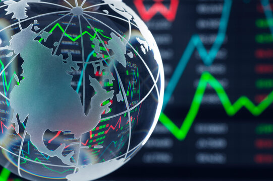 Transparent globe with stock market graphs in the background, featuring red and green lines.