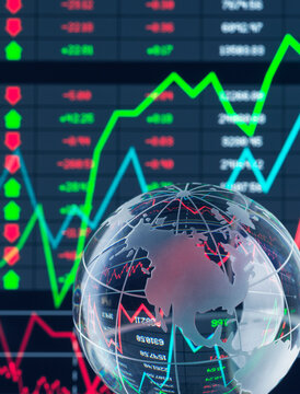 Transparent globe with stock market charts and data in the background.
