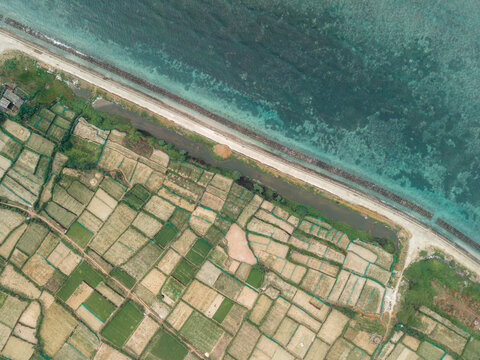 Aerial view of patchwork farmland beside a coastline with clear blue water. Ly Son island, Vietnam