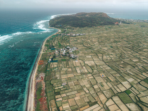 Aerial view of a coastal landscape with patchwork fields and distant hills. Ly Son island, Vietnam