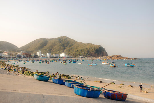 Scenic coastal view with circular boats on the shore and fishing boats in the sea.
