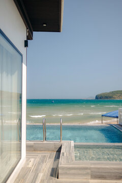 Modern villa pool overlooks a tranquil sea under a clear blue sky.