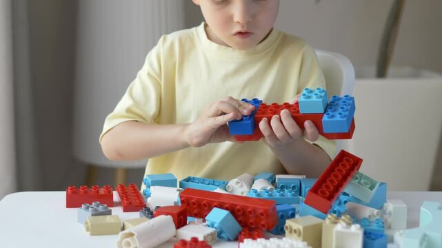 Child builds structure from large interlocking construction bricks during focused play session. Concept of imagination, engineering thinking, hand coordination through educational toys. 