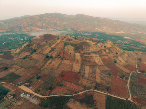 Aerial view of terraced land on a hillside with a mountain range in the background.