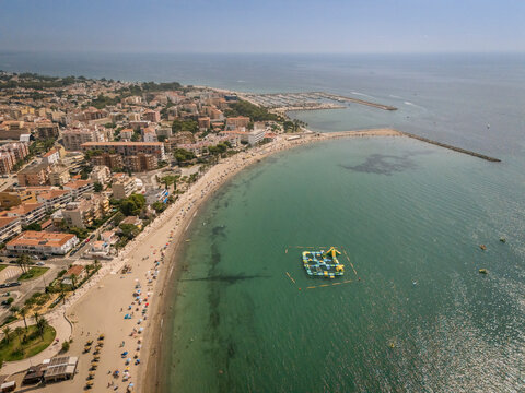 Aerial view of a coastal town with a beach and floating water park in the ocean.