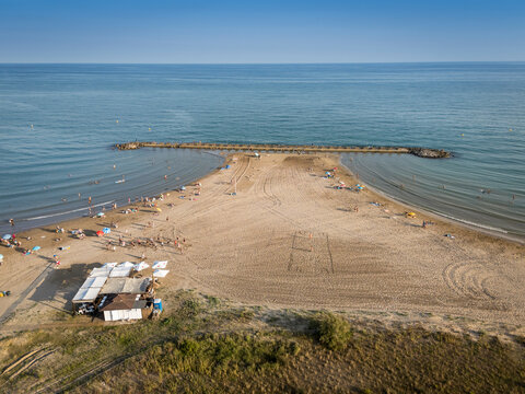 Aerial view of a sandy beach with scattered people and a small beachside structure.