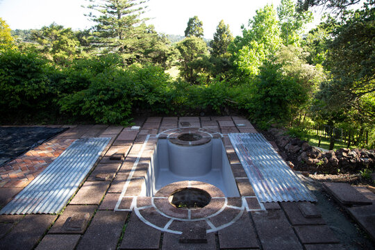 Outdoor hot tub surrounded by trees and paved area with sunlight filtering through. Auckland, New Zealand