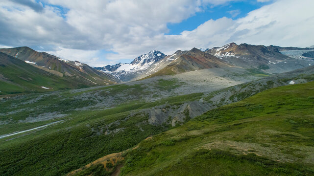 Majestic mountain landscape with lush green valleys and snow-capped peaks under a cloudy sky. Isabel Pass, Alaska, USA