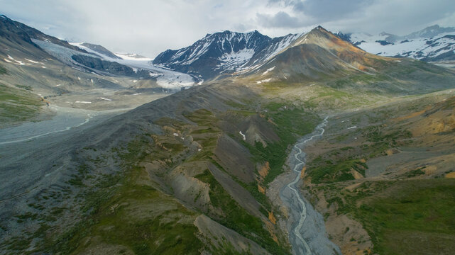 Majestic mountain landscape with snow-capped peaks and flowing rivers under a cloudy sky. Isabel Pass, Alaska, USA