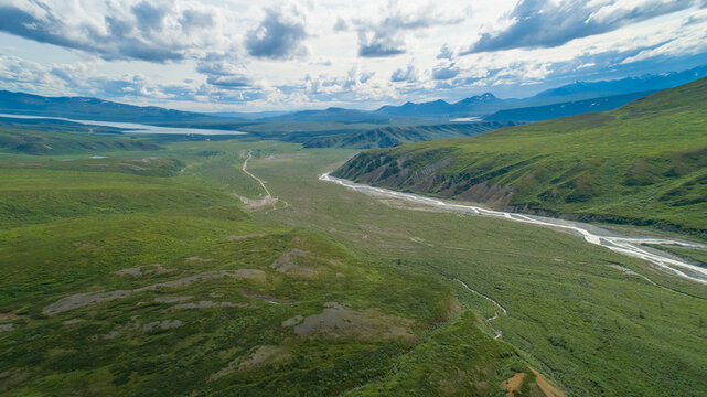 Aerial view of vast green landscapes and winding river under a cloudy sky Isabel Pass, Alaska, USA