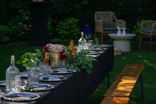 outdoor banquet table catering setup elegant place settings, banquet table decorated with flowers and glassware on lawn, garden party atmosphere with copy space for banner design, concept of event