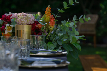 floral centerpiece table setting garden party decor, elegant bouquet with flowers and eucalyptus on banquet table, outdoor celebration atmosphere with copy space for banner design © Lana Pietukhova