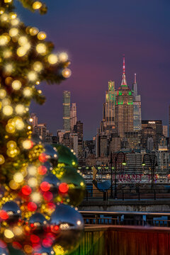New York City skyline at dusk with festive Christmas lights and decorated tree in the foreground. New York, USA