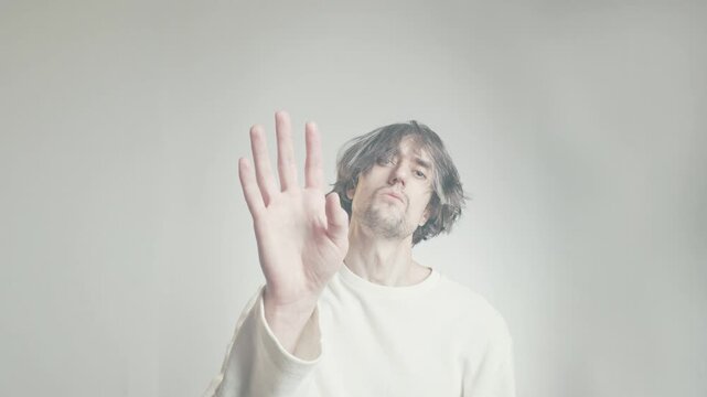 Comedic shaggy-haired man greeting with raised hand and arrogant expression