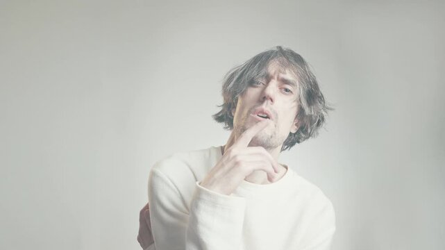 Comical shaggy-haired man in thinker pose with skeptical thoughtful look