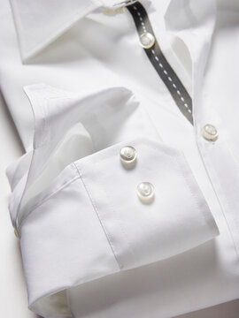 Crisp white dress shirt with folded cuffs and stylish button details.