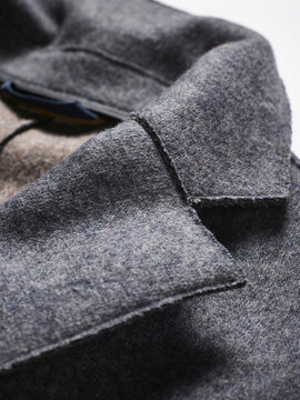 Close-up of a grey wool coat, highlighting the texture and stitching on a collar.
