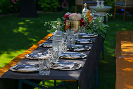 outdoor banquet table catering setup elegant place settings, banquet table decorated with flowers and glassware on lawn, garden party atmosphere with copy space for banner design, concept of event